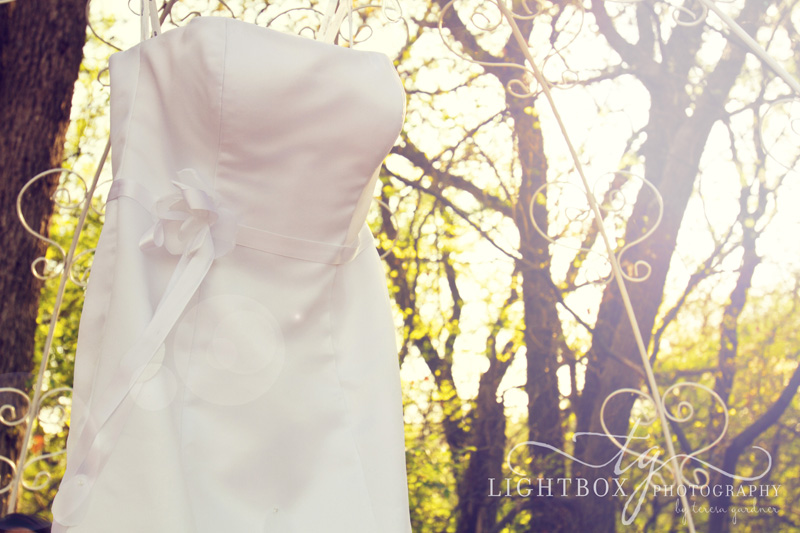 white wedding dress hanging under gazebo with sun shining in Dallas TX